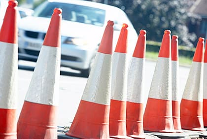 A row of orange and white traffic cones on the side of a road.